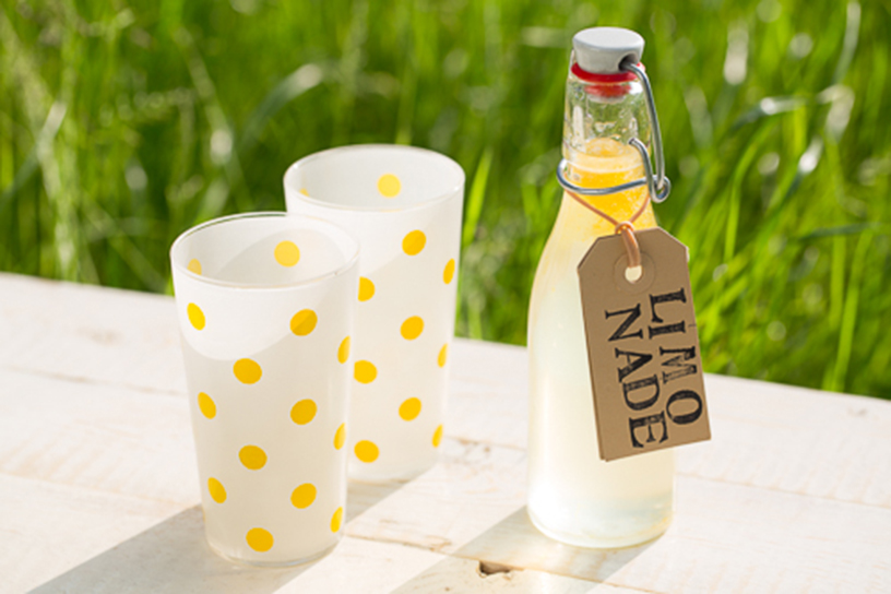 Citroenlimonade in een klein flesje met twee bijpassende witte glazen met gouden stippen